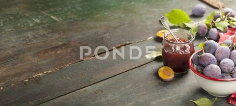 Plums and jar of jam on table Stock Photos