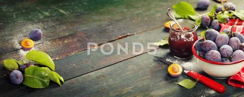 Plums and jar of jam on table Stock Photos