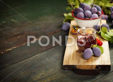 Plums and jar of jam on table Stock Photos