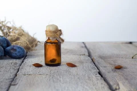 Plums bones' kernels essential oil with ripe plums on white rustic background Stock Photos