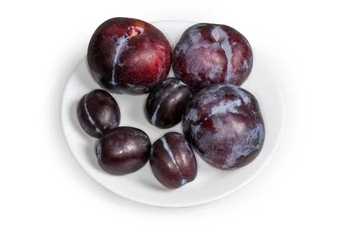 Plums different varieties and sizes on plate on white background Stock Photos