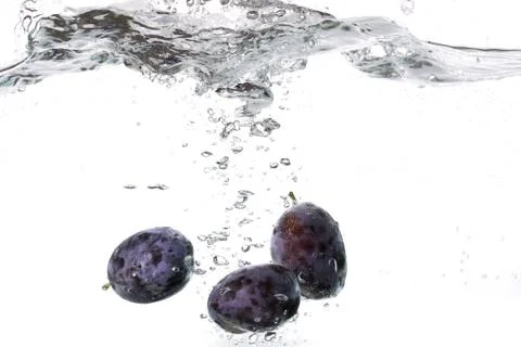 Plums falling into water Stock Photos