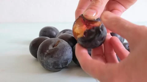 Plums for pie. Women's hands open a ripe plum Stock Footage 284959210