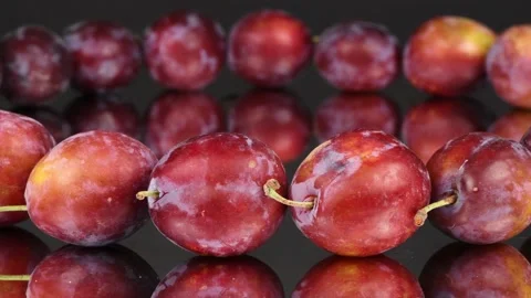 Plums in a row on black mirror. Side view. Loop motion. Rotation 360. Stock Footage 161318739