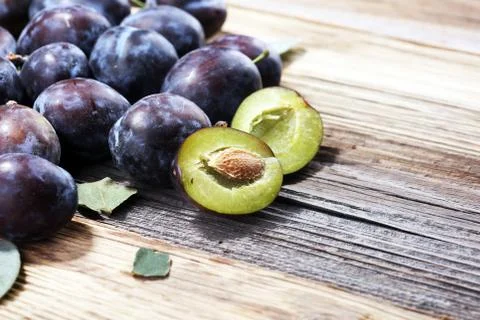 Plums on rustic background. Half of blue plum fruit. Many beautiful plums wit Stock Photos
