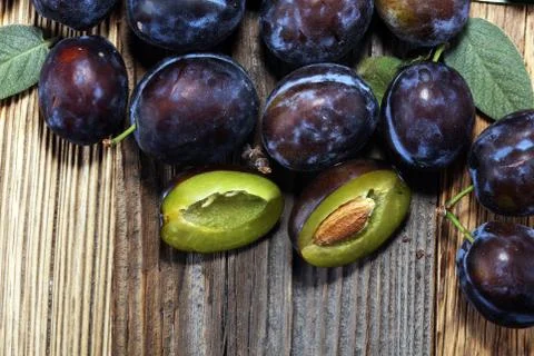 Plums on rustic background. Half of blue plum fruit. Many beautiful plums wit Stock Photos