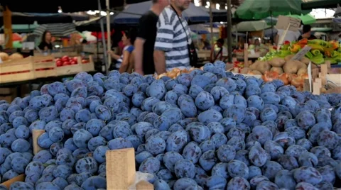Plums on the stall close up, people passing to the market place in background,4k Stock Footage 54404539