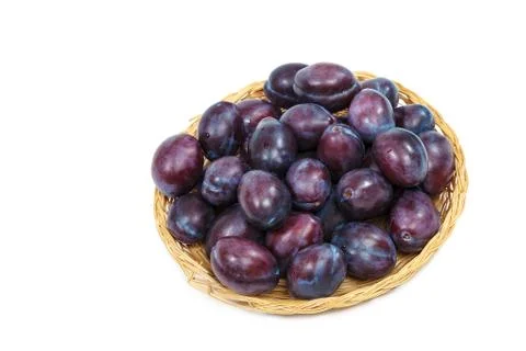 Plums in a wicker dish on a white background Stock Photos