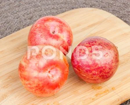 Pluots on wood cutting board. Stock Photos