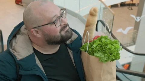 Plus size Caucasian bearded man in glasses standing on escalator carrying Stock Footage 264167948