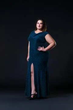 Plus size fashion model in green evening dress, fat woman on black background Stock Photos