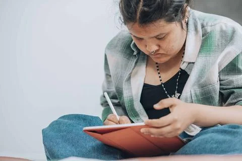 Plus-size freelancer engrossed in her project on a tablet, emphasizing the Stock Photos