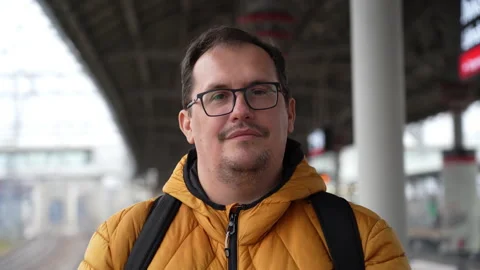 Plus size guy looking to camera with serious expression while waiting for train Stock Footage 169412820