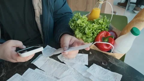 Plus size man reviewing receipts and calculating grocery expenses using Stock Footage 285537474