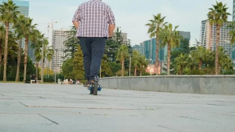 Plus size man riding electric scooter in the city. Rear view of male driving e Stock Footage 270587153