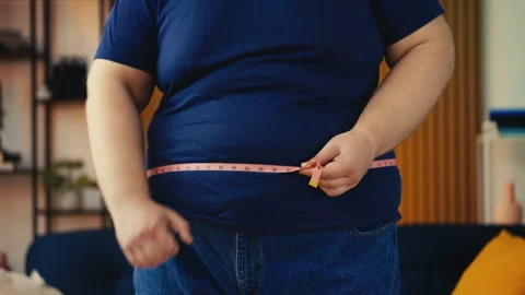 Plus-size man using tape to measure waist, frustrated by weight gain and obesity Vídeo Stock 310003326