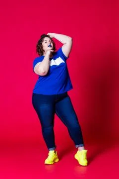 Plus size model in casual clothes, fat woman in blue jeans and t-shirt on red Stock Photos