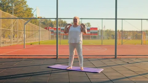 Plus size woman doing shoulder mobility exercises on outdoor court. fitness and Video stock 340993059