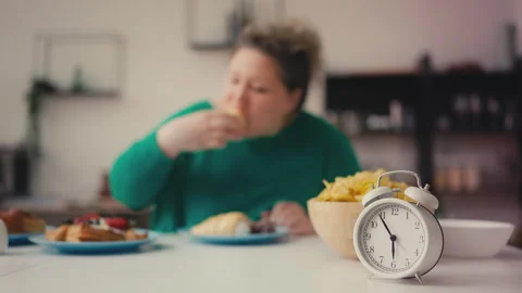 Plus size woman overeating sweets and junk food before 6pm intermittent fasting