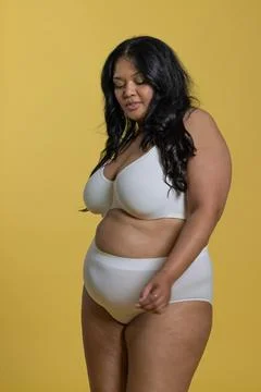 Plus-size woman posing in white supportive bra and high-waist briefs against Stock Photos