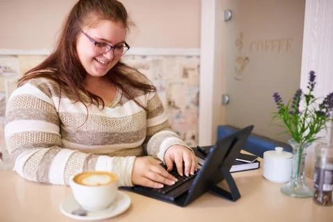 Plus size woman smiling while working in a bright cafe Foto stock