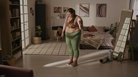 Plus-size Woman Stepping on Scale for Weight Loss Progress Stock Footage 337908095