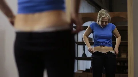Plus size woman trying to squeeze into old pants Stock Footage 83389607