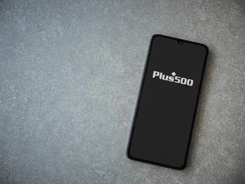 Plus500 app launch screen with logo on the display of a black mobile smartpho Stock Photos