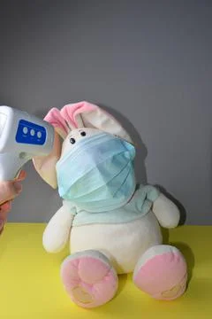 A plush hare in a mask. Measuring the temperature of the toy. Stock Photos