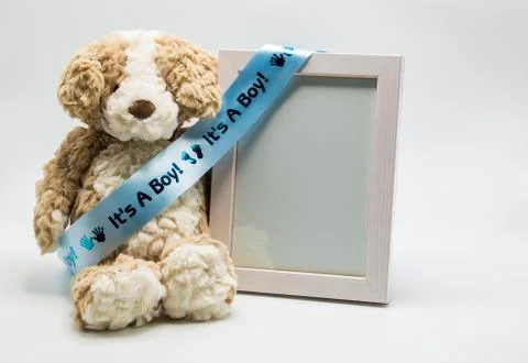 Plush teddy bear and empty picture frame with blue "It's A Boy" ribbon Stock Photos