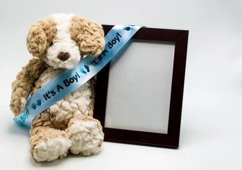 Plush teddy bear and empty picture frame with blue "It's A Boy" ribbon Stock Photos