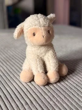Plush toy lamb on gray corduroy sofa in soft daylight close-up. Cozy home i.. Stock Photos