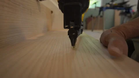 Pneumatic brad nailer securing a wood panel or trim piece into place. Nail gun Stock Footage 320143059