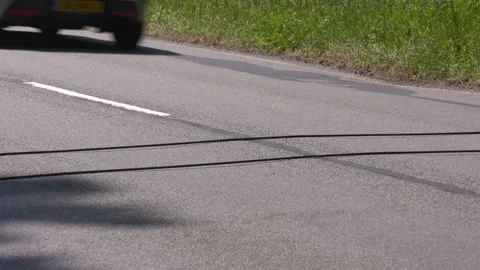 Pneumatic road tubes, cables lay across the road, vehicles passing by Stock Footage 243068993