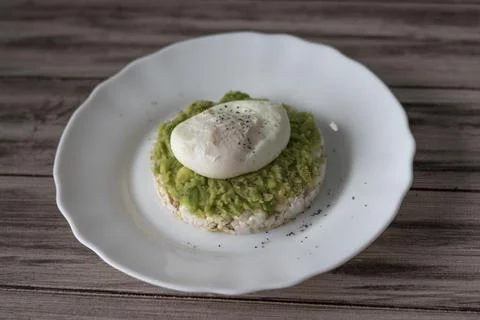 Poached egg with bread and avocado on a white plate and brown wooden backgrou Stock Photos