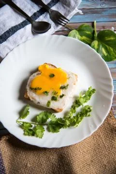 Poached egg on bread slice with condiments on a white plate Stock Photos