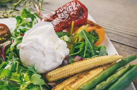 Poached egg with corn vegetables, grilled pepper, spinach, arugula, green bea Stock Photos