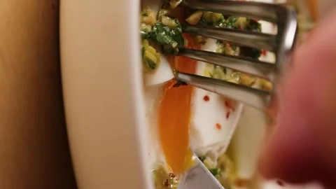 The poached egg is cut with a knife and the yolk flows out delicious Stock Footage 263730128