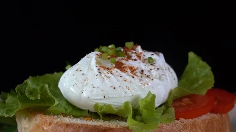 Poached egg on a piece of bread with green lettuce leaves on a plate, close up Stock Footage 94932754