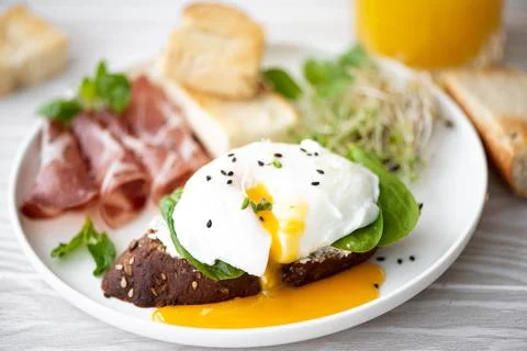 Poached egg with rye bread, ham and herbs Stock Photos