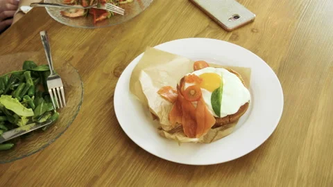 Poached egg, salmon, caviar, spinach leaves on toast bread, vegetable salad. 4K Stock Footage 110219186