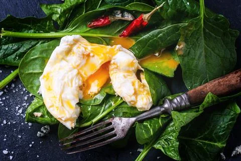 Poached egg served with red hot chili peppers and vintage fork on fresh spi.. Stock Photos