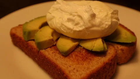 Poached Egg on Sliced Avocado Toast with Knife Cutting Open Stock Footage 127260576