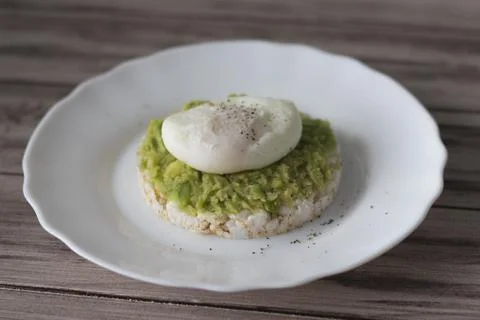 Poached eggs on bread with avocado on a brown wooden table Foto stock