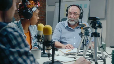 Podcast Co-Hosts Interviewing Senior Male Guest at Recording Studio Stock Footage 246331669