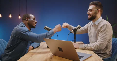 Podcast hosts fist bumping while recording a live interview, agreement on air Stock Footage 328973377