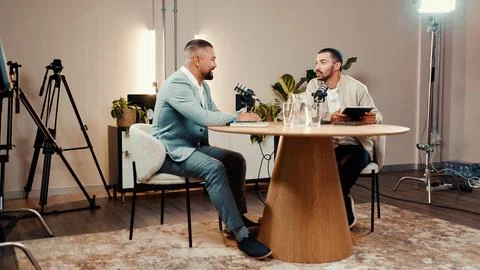 Podcast, men and talk for interview in studio, business show and laugh at f.. Stock Photos