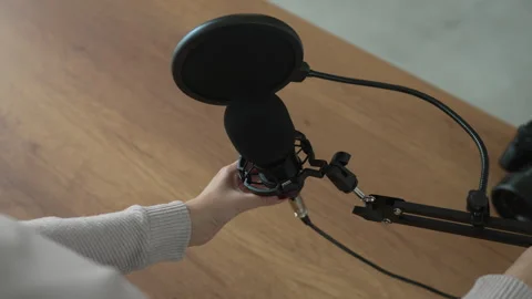 Podcast microphone set up with pop filter on wooden desk at home studio Stock Footage 293845159