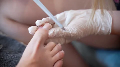 Podiatrist master in white gloves using sterile hardware file to polish toe nail Stock Footage 230672486