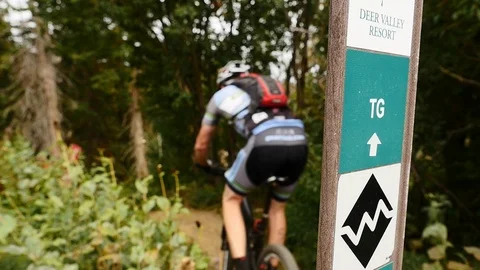 Point 2 Point Mountain Bike Race competitor rides past Deer Valley Resort sign. Stock Footage 106789641